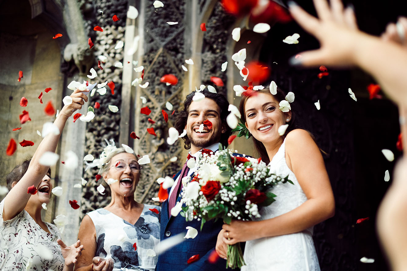 family throwing rose petals at the newly wed bride